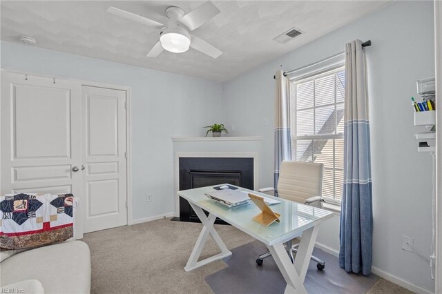 office space with visible vents, carpet floors, baseboards, and a ceiling fan