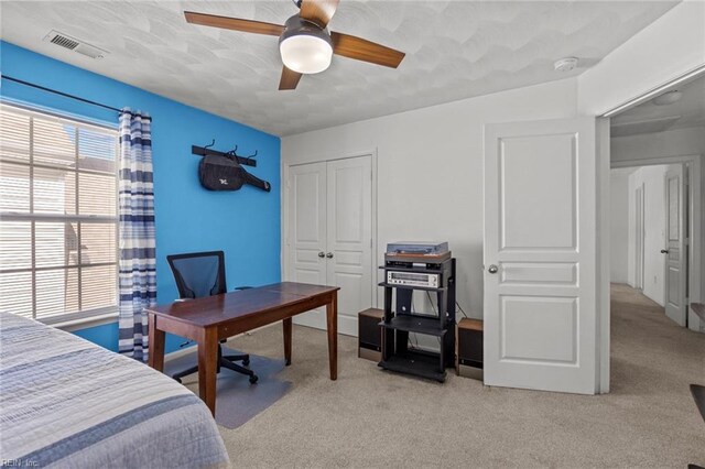 carpeted bedroom with a closet, visible vents, and ceiling fan