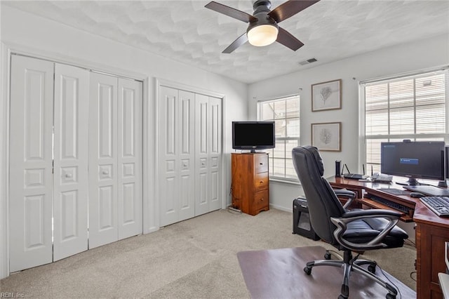 office featuring a ceiling fan, carpet, visible vents, and a textured ceiling