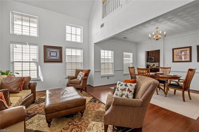 living area with visible vents, dark wood finished floors, crown molding, baseboards, and a chandelier