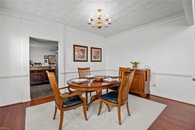 dining room with an inviting chandelier, ornamental molding, and hardwood / wood-style flooring