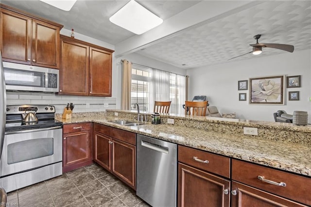 kitchen featuring a ceiling fan, a sink, light stone counters, tasteful backsplash, and stainless steel appliances