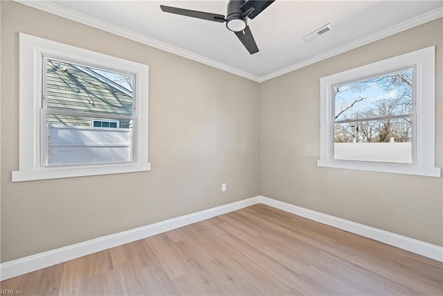 empty room featuring wood finished floors, plenty of natural light, baseboards, and visible vents