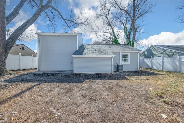 back of house with dirt driveway, central AC, and fence