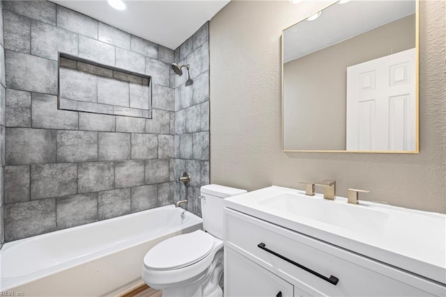 full bathroom featuring toilet, vanity, bathtub / shower combination, and a textured wall