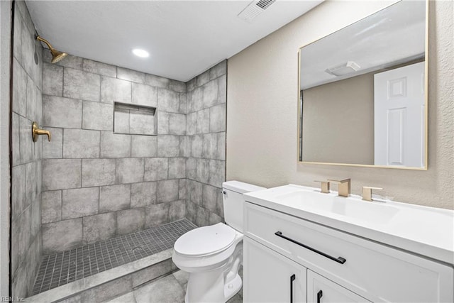 bathroom with vanity, toilet, visible vents, and a stall shower