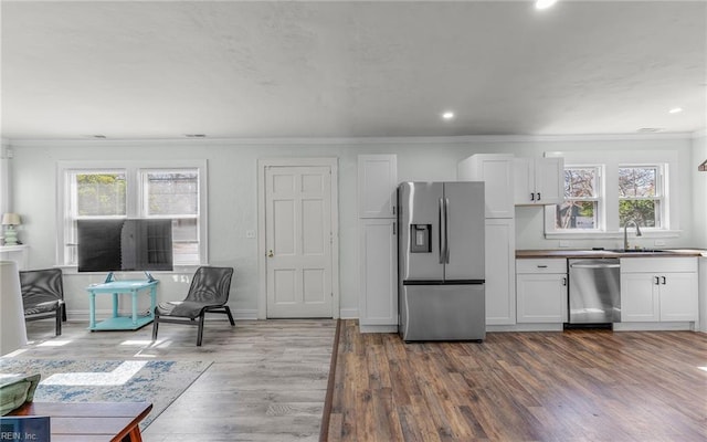 kitchen with white cabinets, ornamental molding, a wealth of natural light, and stainless steel appliances