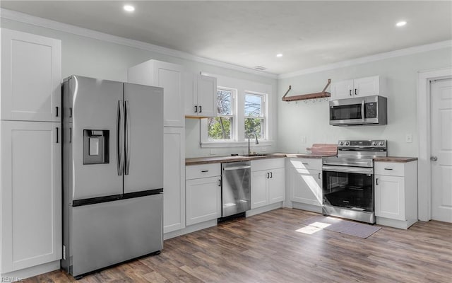 kitchen featuring a sink, crown molding, white cabinets, and stainless steel appliances