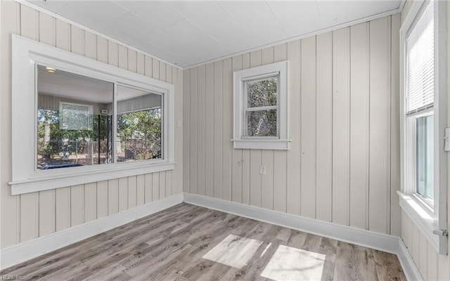 spare room with baseboards and wood finished floors