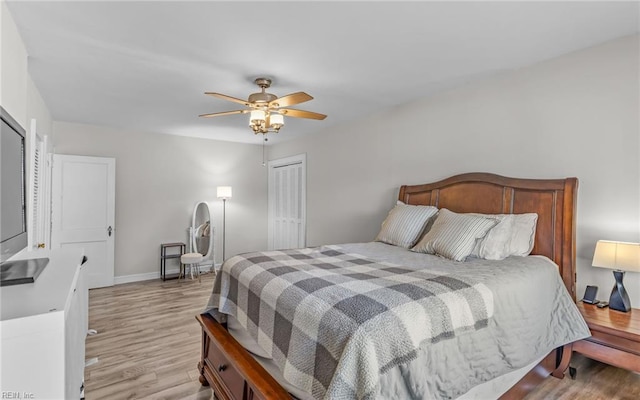 bedroom with a closet, baseboards, a ceiling fan, and light wood finished floors