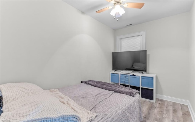 bedroom featuring visible vents, ceiling fan, baseboards, and wood finished floors