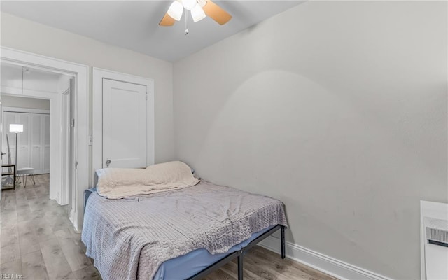 bedroom with attic access, baseboards, light wood-type flooring, and ceiling fan