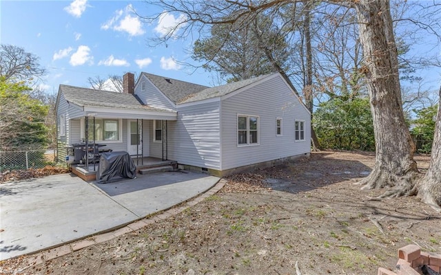 view of front of house featuring a patio area, a shingled roof, a chimney, and fence