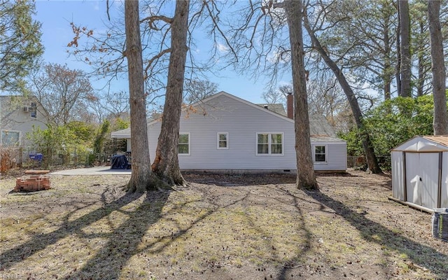 view of side of property with a storage unit, an outbuilding, a patio, fence, and crawl space