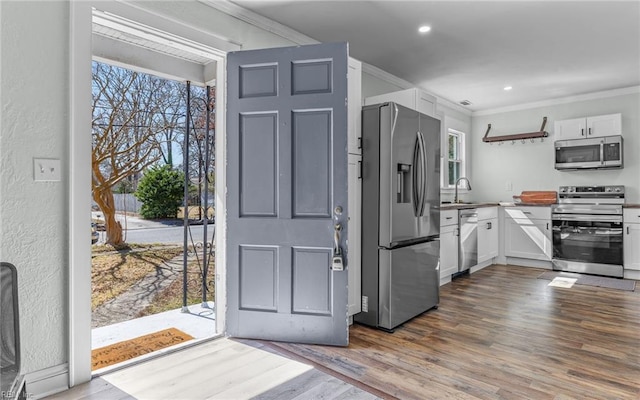 kitchen with crown molding, dark wood-style flooring, and appliances with stainless steel finishes