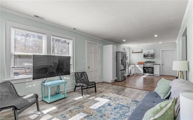 living area featuring visible vents, ornamental molding, recessed lighting, light wood-style floors, and baseboards