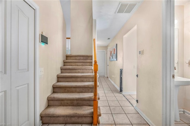 stairway with tile patterned floors, baseboards, and visible vents