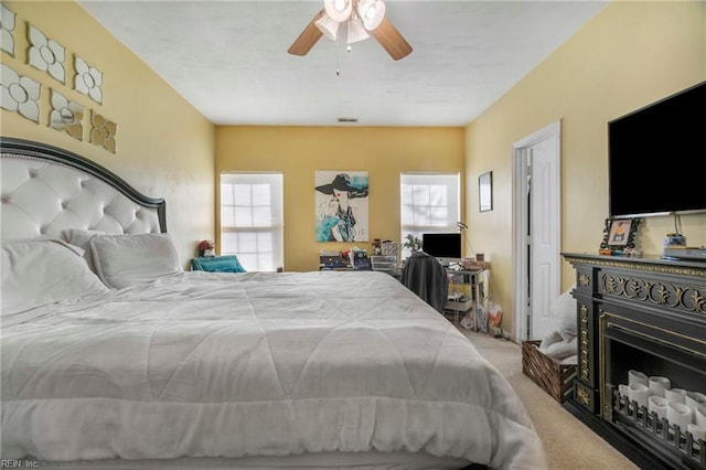 bedroom featuring a ceiling fan, carpet flooring, a fireplace, and visible vents