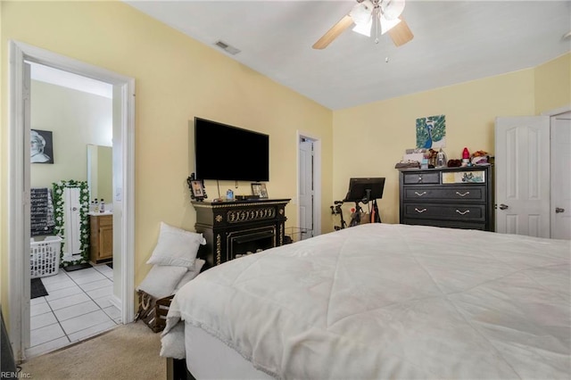 carpeted bedroom with visible vents, ensuite bath, and ceiling fan