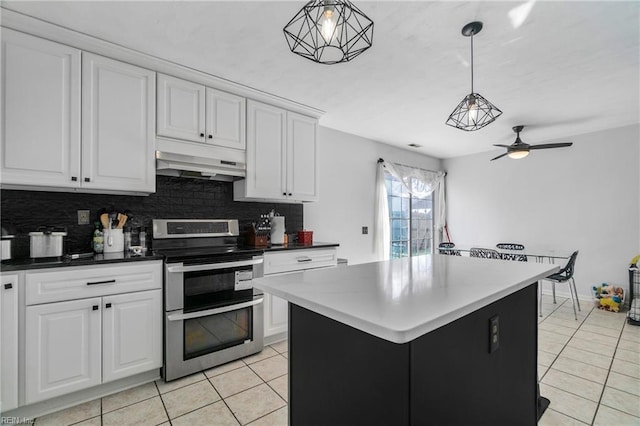 kitchen with under cabinet range hood, backsplash, white cabinetry, and range with two ovens