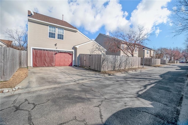 exterior space with a garage, concrete driveway, and fence