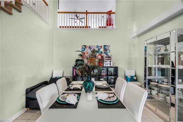 tiled dining area featuring baseboards and a towering ceiling