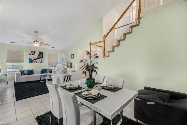 dining space featuring light tile patterned floors, visible vents, lofted ceiling, ceiling fan, and stairs