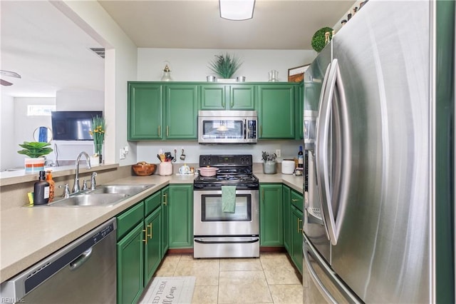 kitchen featuring green cabinetry, stainless steel appliances, light countertops, and a sink