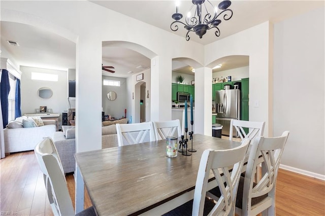 dining room featuring visible vents, baseboards, light wood-style floors, and ceiling fan with notable chandelier