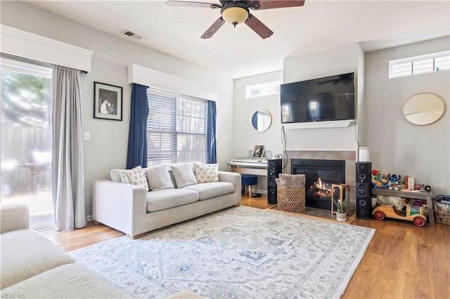 living area featuring visible vents, plenty of natural light, wood finished floors, and a tile fireplace