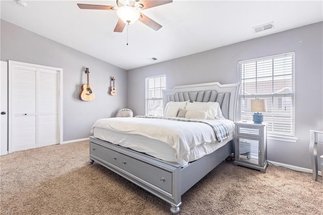 carpeted bedroom with visible vents, baseboards, and ceiling fan