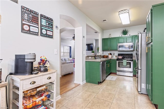 kitchen with a ceiling fan, visible vents, green cabinetry, a sink, and stainless steel appliances