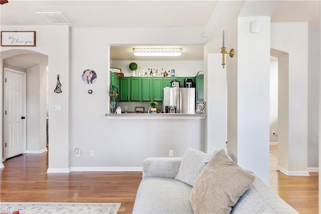 living room featuring light wood-style flooring, baseboards, and visible vents