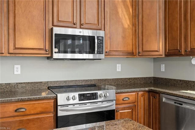 kitchen featuring dark stone countertops, brown cabinets, and stainless steel appliances