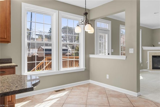 unfurnished dining area featuring a wealth of natural light, a chandelier, baseboards, and light tile patterned flooring