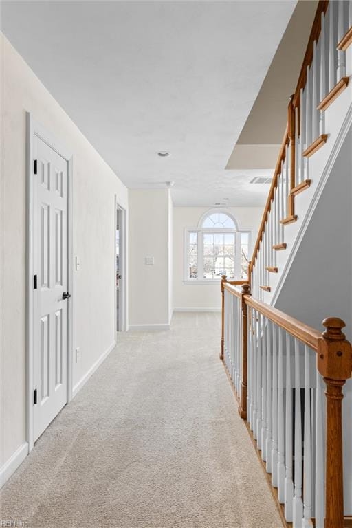 hall with baseboards, light carpet, and visible vents