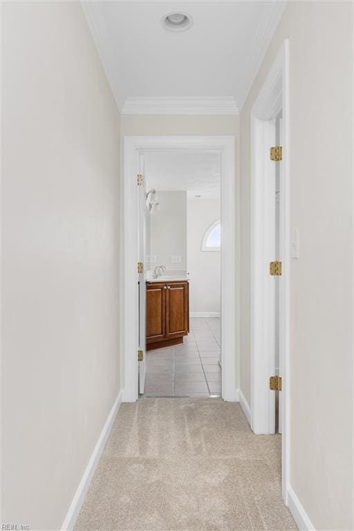 corridor with light colored carpet, baseboards, and ornamental molding