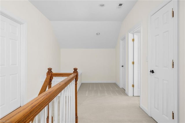 hallway featuring visible vents, baseboards, light colored carpet, vaulted ceiling, and an upstairs landing