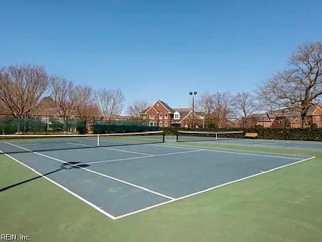 view of tennis court featuring community basketball court and fence