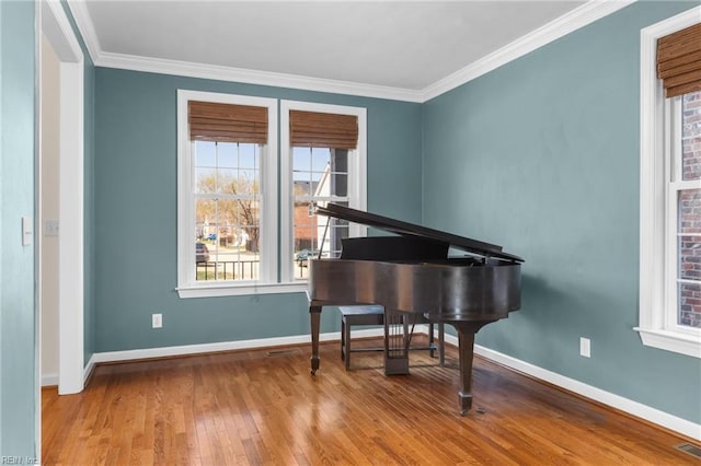 sitting room with hardwood / wood-style floors, visible vents, baseboards, and ornamental molding