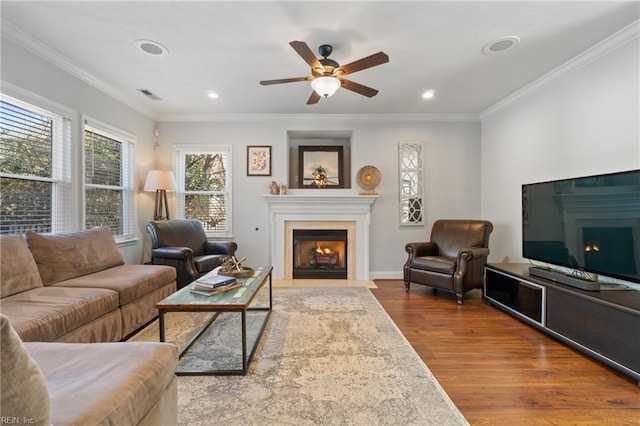 living area with visible vents, a fireplace with flush hearth, ornamental molding, wood finished floors, and recessed lighting