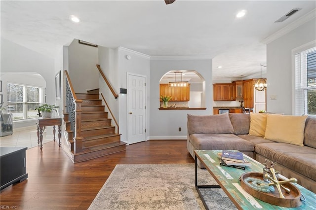 living room featuring visible vents, a healthy amount of sunlight, crown molding, wood finished floors, and arched walkways