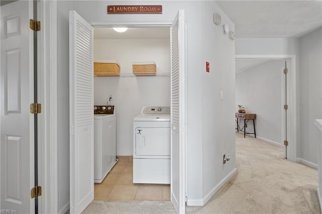 laundry area featuring light tile patterned floors, baseboards, light colored carpet, laundry area, and washing machine and clothes dryer