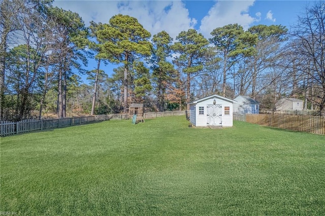 view of yard with a playground, an outdoor structure, a storage shed, and a fenced backyard