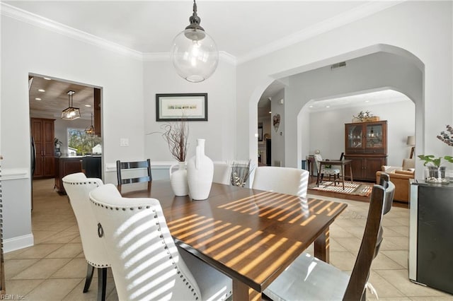 dining area featuring light tile patterned floors, visible vents, arched walkways, and crown molding