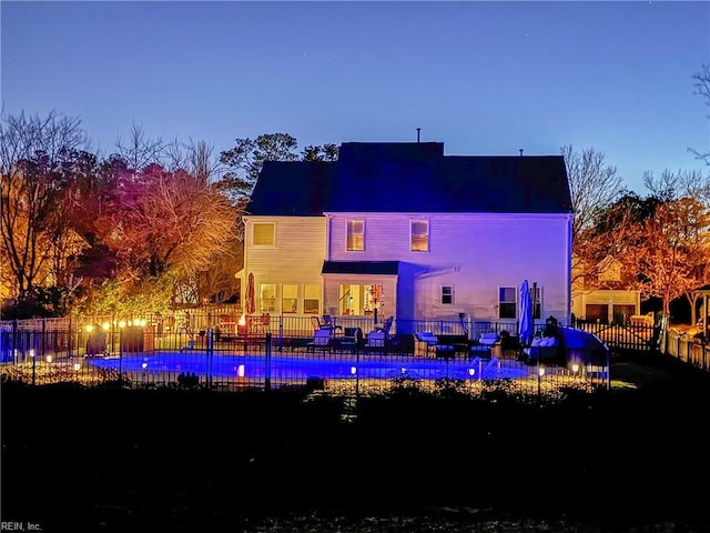 rear view of house with a fenced in pool and fence