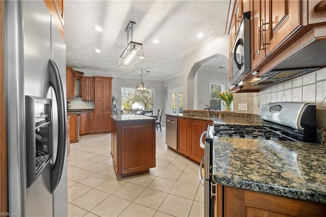 kitchen featuring brown cabinets, a sink, backsplash, stainless steel appliances, and light tile patterned floors