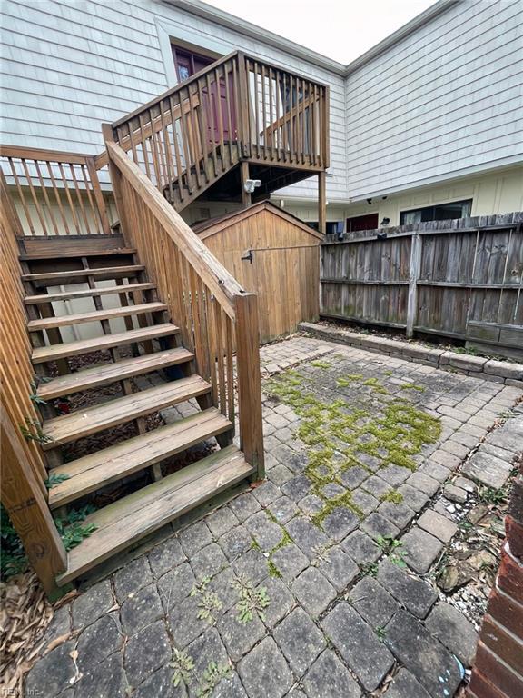 view of patio featuring a storage unit, stairway, an outdoor structure, and fence