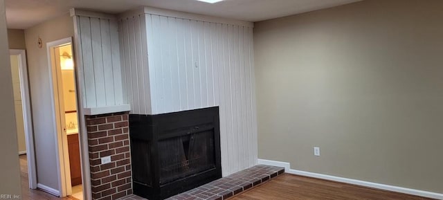 room details featuring a fireplace with raised hearth, baseboards, and wood finished floors