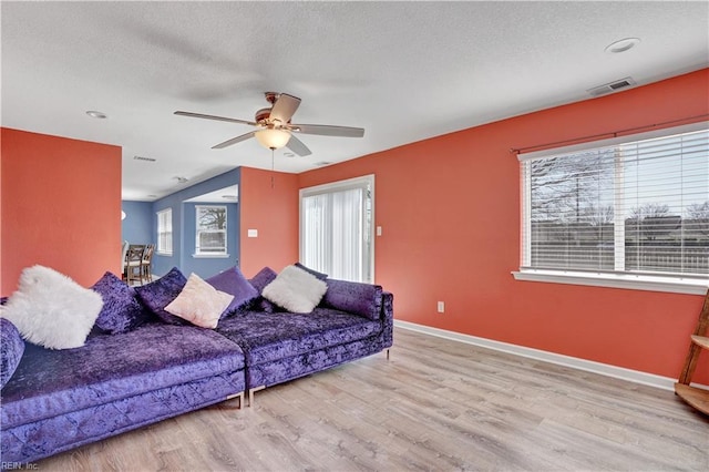 living area featuring visible vents, a textured ceiling, baseboards, and wood finished floors